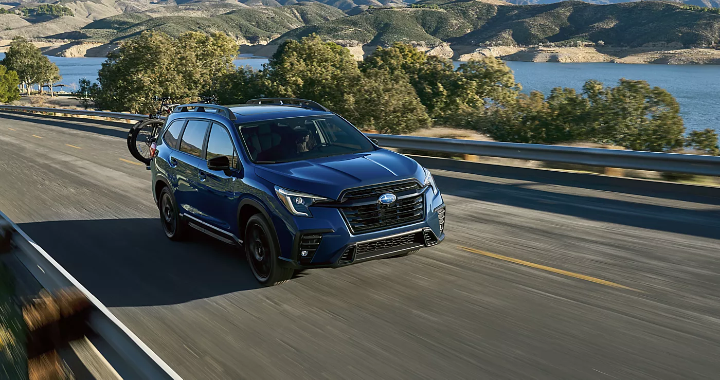 A blue Subaru Ascent driving through a winding backroad.