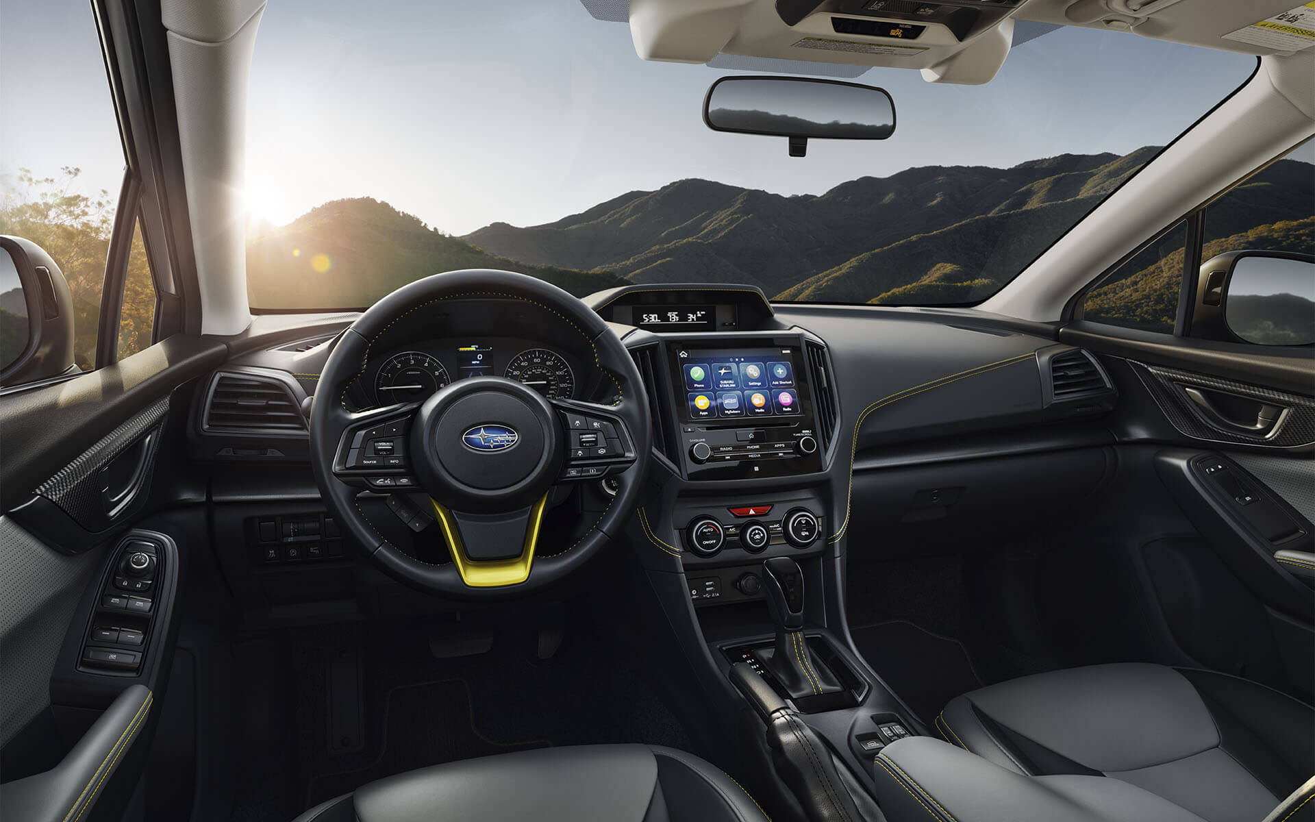 Interior view of a Subaru Forester driving on a mountain road at sunset, showing the dashboard and steering wheel.