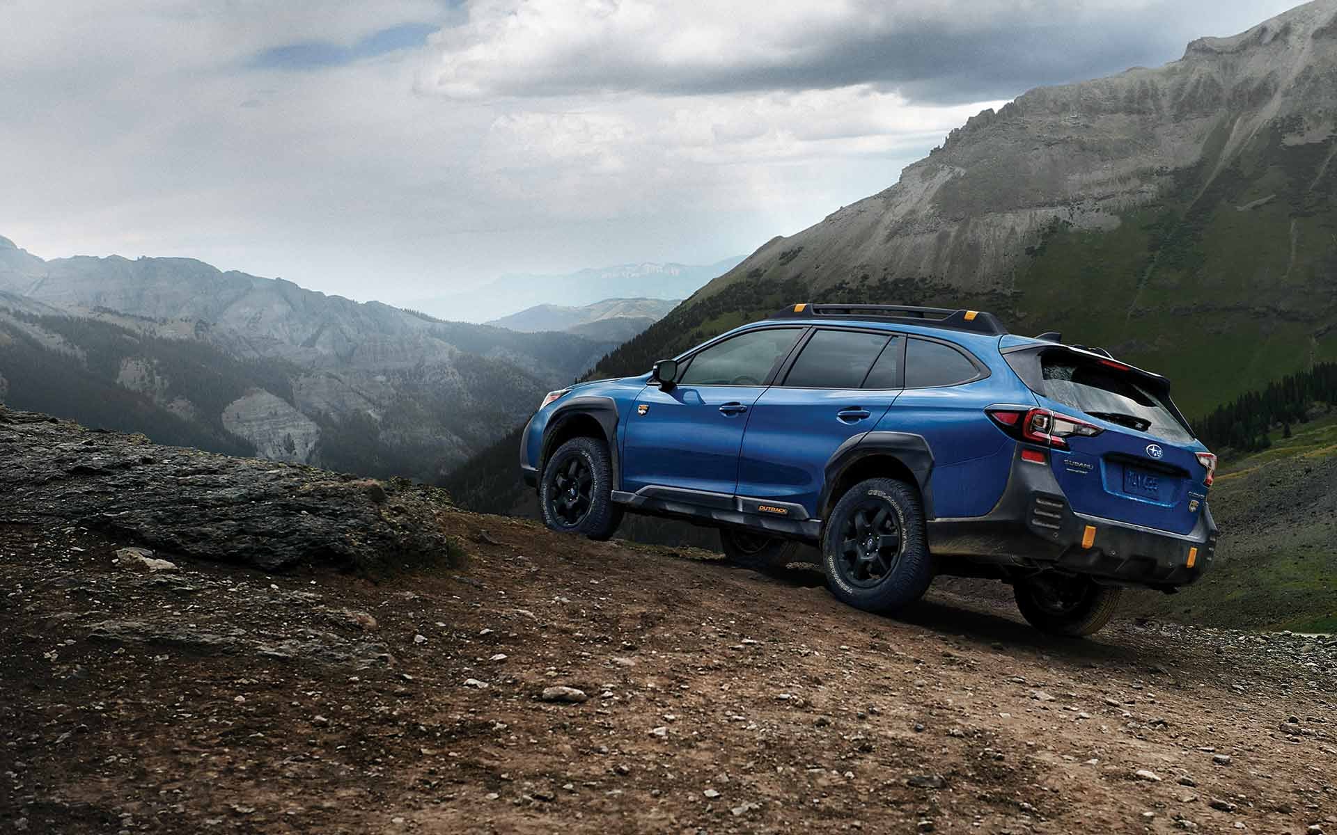 Blue Subaru Outback Wilderness on a dirt road in mountains.