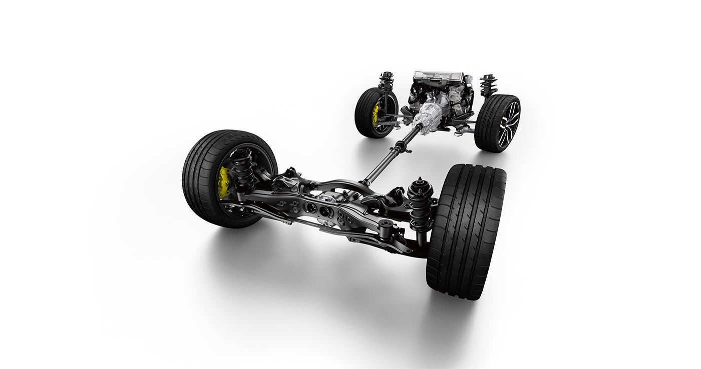 Top-down view of a car's engine, drivetrain, rear differential, and suspension system with wheels, on a white surface.