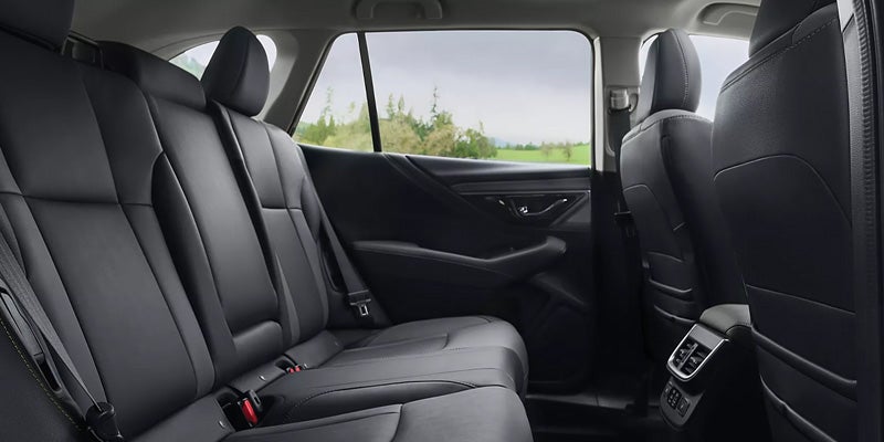 Interior view of a car with dark grey or black leather back seats, seen from the right rear side.