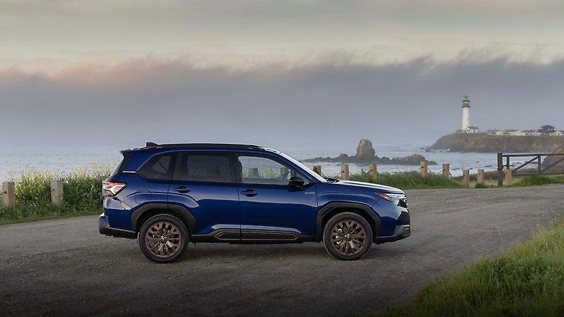 2025 Subaru Forester Hybrid in blue, three-quarter view near a lighthouse