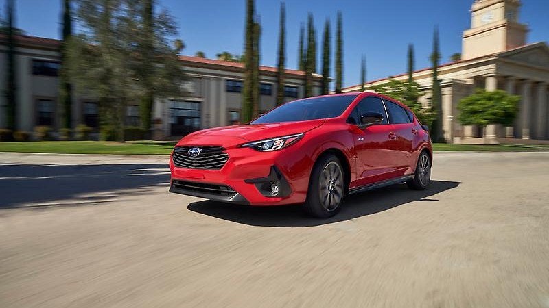 2024 Subaru Impreza in red, three-quarter view on a scenic road