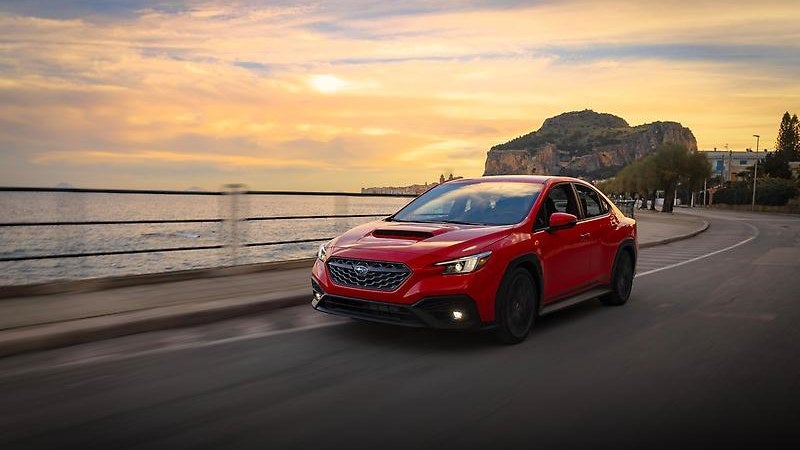 2025 Subaru WRX in red, front three-quarter on a coastal road