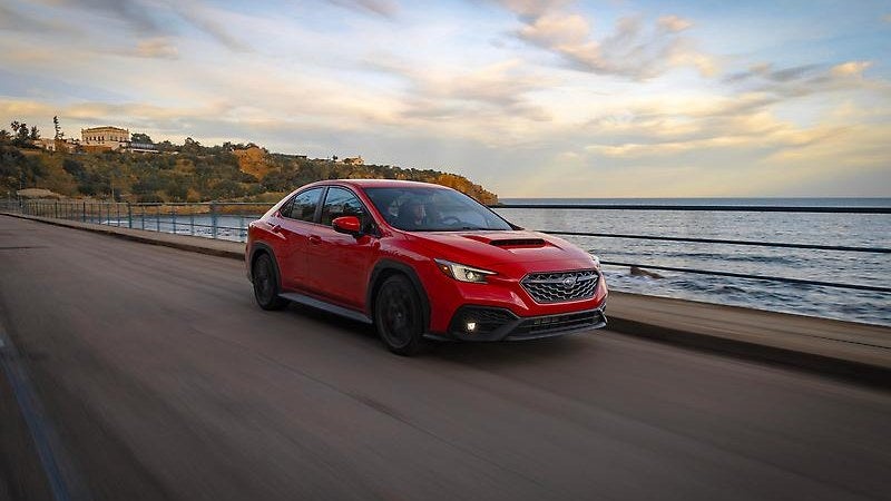 Subaru WRX in red, side three-quarter on a coastal road